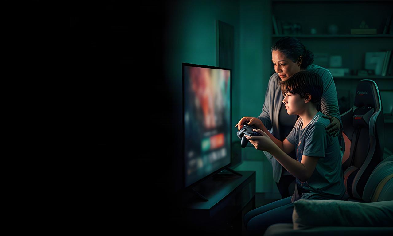 Parent and teenage player reviewing game settings together beside a television in a dimly lit gaming room